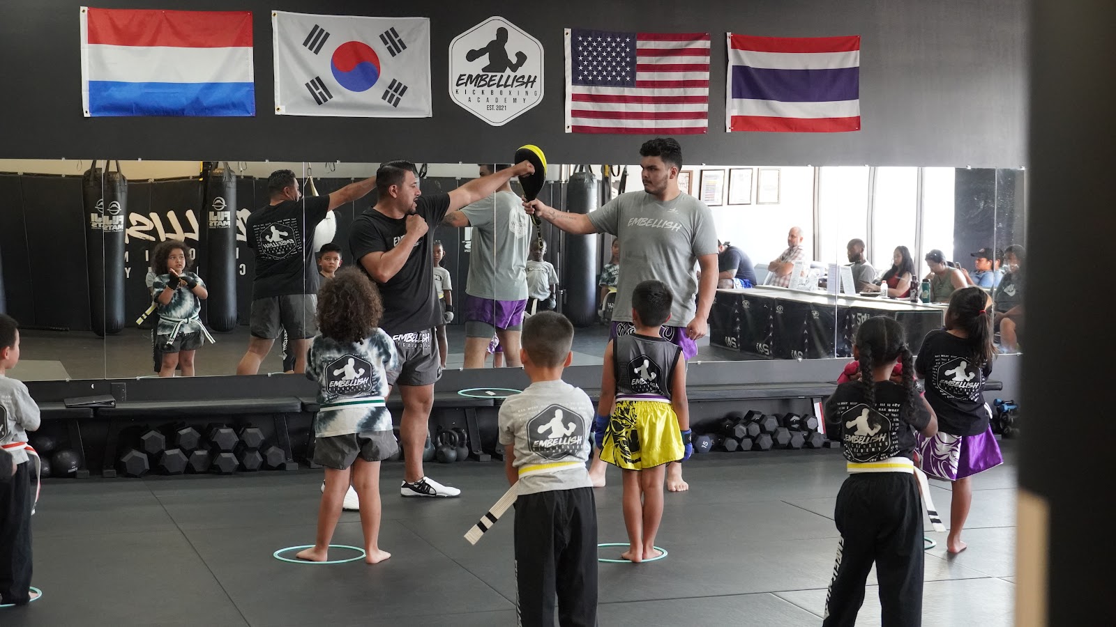 Parents watching a class from the side of the mat at Embellish Kickboxing Academy in Elk Grove.